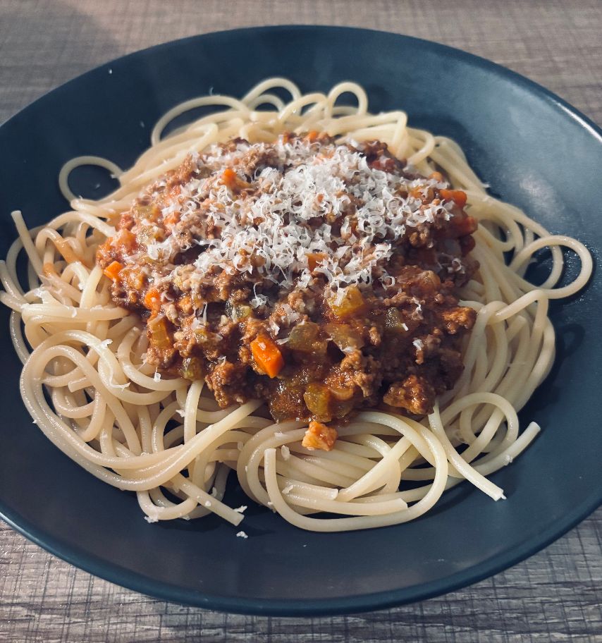 Spaghetti Bolognese angerichtet auf einem Teller garniert mit Parmesan